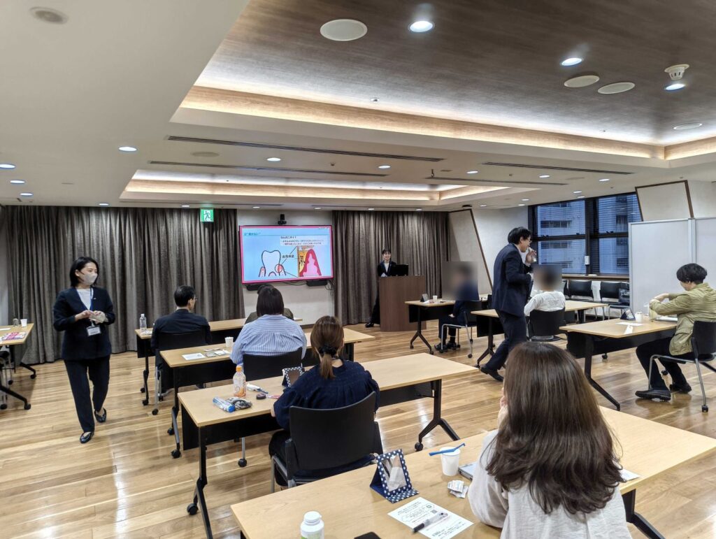 エフエム東京様の会場で、歯科衛生士の講義を聞きながら参加者が口腔ケアを体験する様子